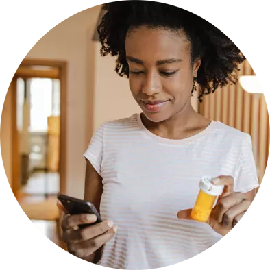 Young woman holding a smartphone and a box of pills